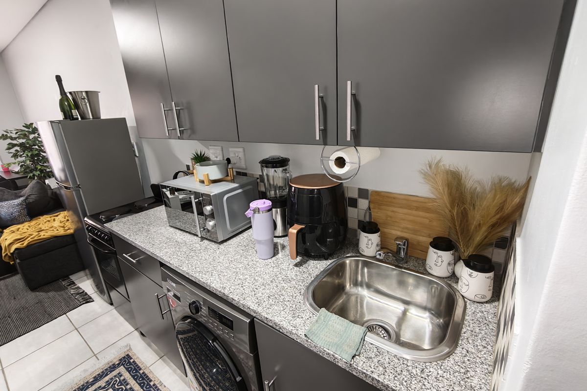 Modern kitchen featuring grey cabinetry, granite countertops, a stainless steel sink, and integrated appliances including a washing machine and oven.
