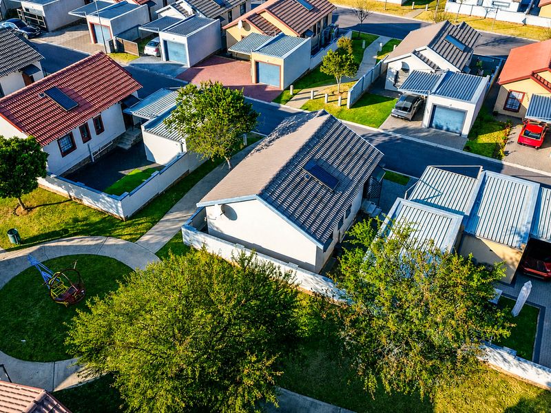 An aerial view of a residential estate showing multiple detached houses with tiled roofs, paved driveways, and private garden areas.