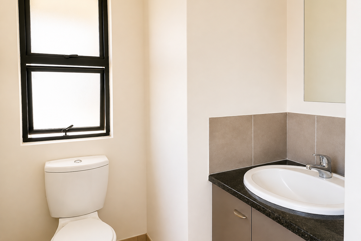 A clean and modern bathroom featuring a vanity with granite countertop, drop-in sink, wall mirror, and a toilet.