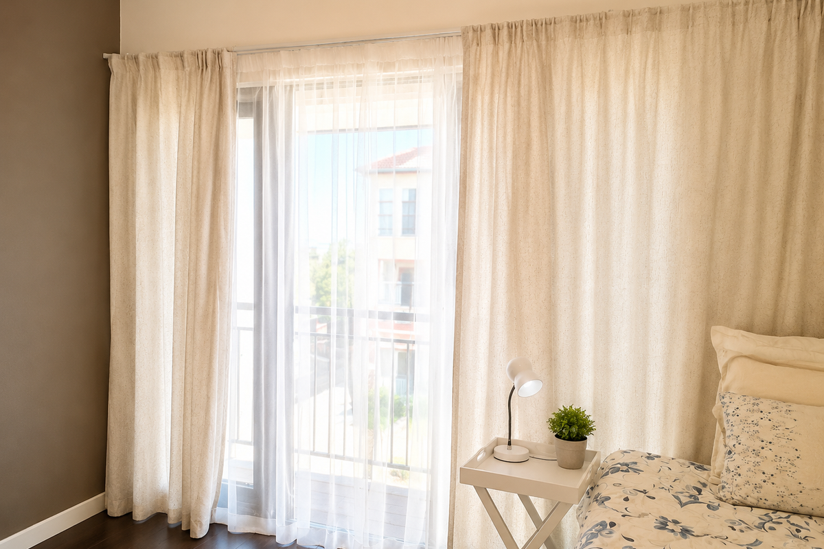 A bright bedroom featuring dark laminate flooring and a large sliding glass door that provides access to an outdoor balcony area.