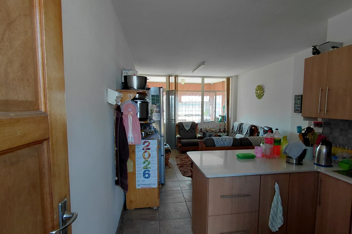 Open-plan living area featuring a functional kitchen with island cabinetry and tiled flooring, leading directly to an enclosed patio space.
