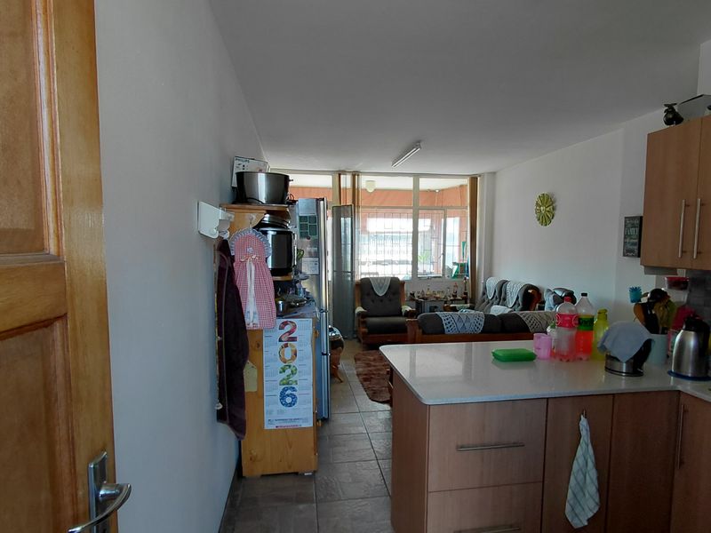 Open-plan living area featuring a functional kitchen with island cabinetry and tiled flooring, leading directly to an enclosed patio space.