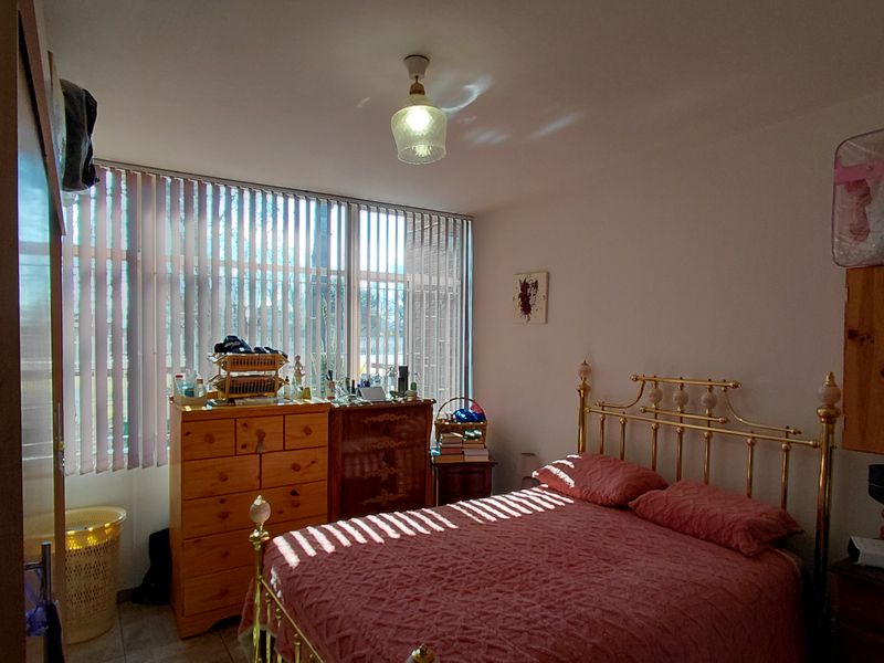 A standard bedroom featuring a large window with vertical blinds and neutral wall finishes, offering a functional space with natural light.