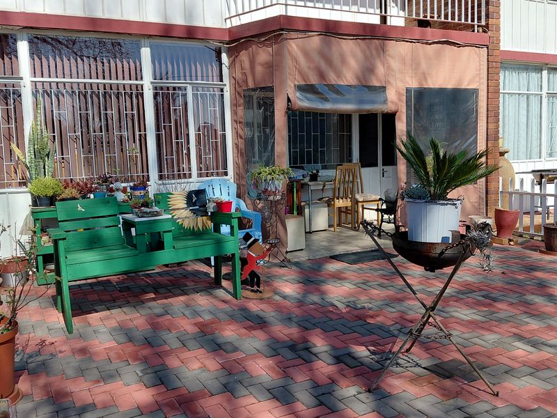 A paved outdoor patio area featuring a canvas enclosure and security bars on the windows, providing a functional space for outdoor relaxation.