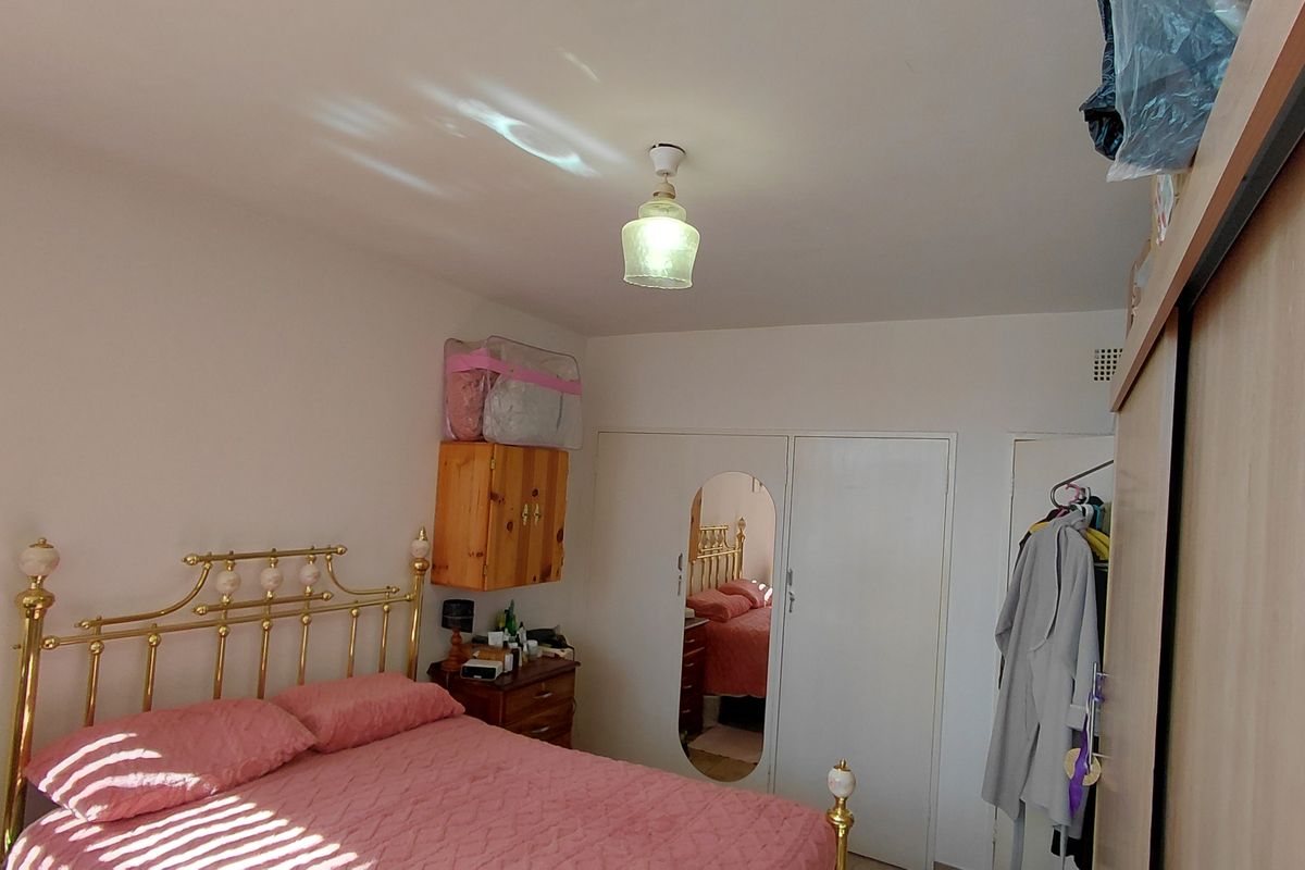 A functional bedroom featuring a built-in wardrobe with mirrored panel and a central ceiling light fixture.