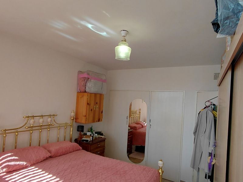 A functional bedroom featuring a built-in wardrobe with mirrored panel and a central ceiling light fixture.