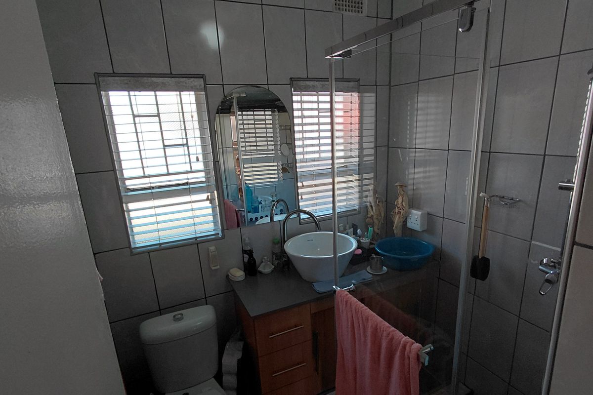 A functional bathroom featuring a vessel sink vanity, glass-enclosed shower, and tiled finishes throughout, providing a practical layout for daily use.