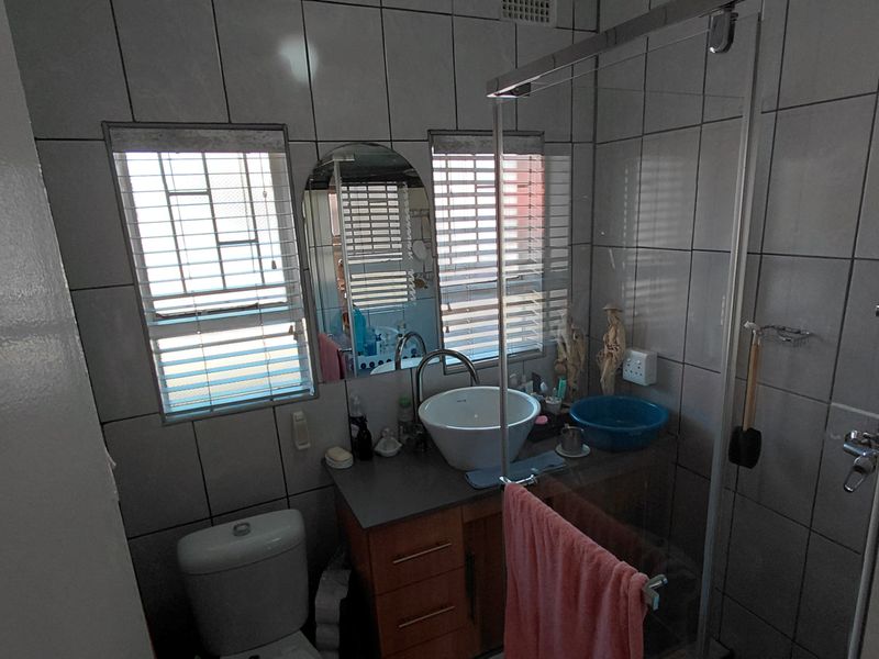 A functional bathroom featuring a vessel sink vanity, glass-enclosed shower, and tiled finishes throughout, providing a practical layout for daily use.