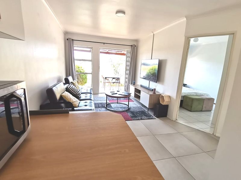 Open plan living area featuring tiled flooring and a sliding glass door leading to an outdoor patio space.