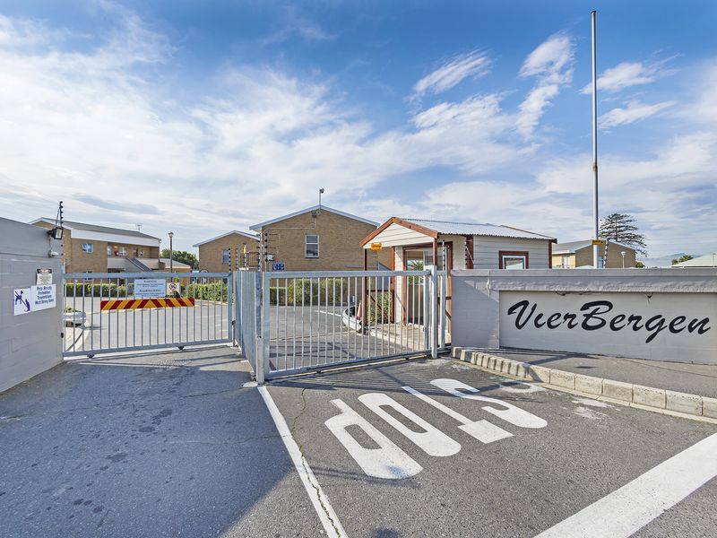 The secure entrance to the Vierbergen townhouse complex, featuring a gated access point, security booth, and perimeter walling.