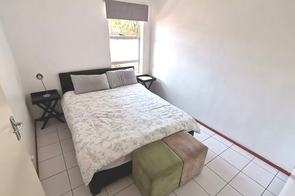 A compact bedroom featuring tiled flooring and a window with a fitted roller blind.