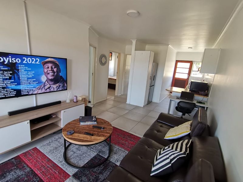 Open-plan living area featuring tiled floors, a functional kitchen layout with breakfast counter, and direct access to adjacent rooms.