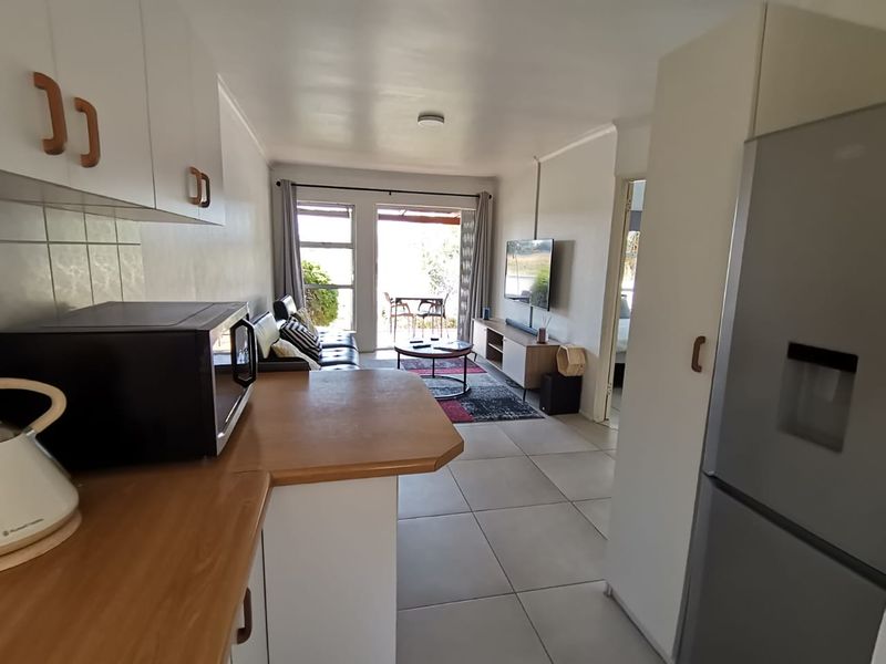 Open-plan kitchen and living area featuring tiled floors, built-in cabinetry, and direct access to an outdoor patio through a sliding glass door.
