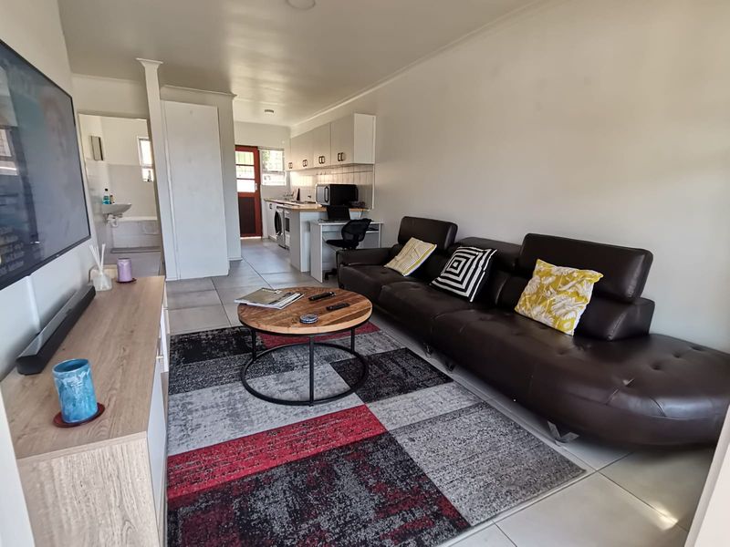 Open-plan living area featuring tiled flooring and a functional kitchen space with built-in cabinetry and countertops.