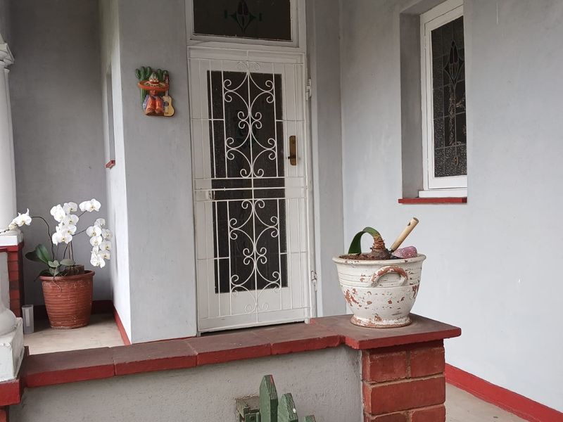 Front entrance area featuring a security gate, leaded glass window, and a covered porch with brick and concrete detailing.