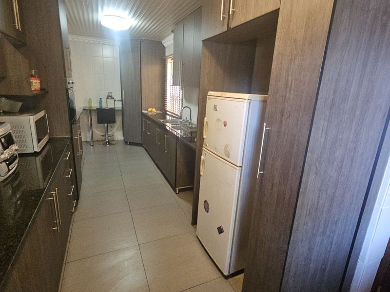 A functional galley-style kitchen featuring dark wood cabinetry, granite countertops, tiled flooring, and integrated storage space.