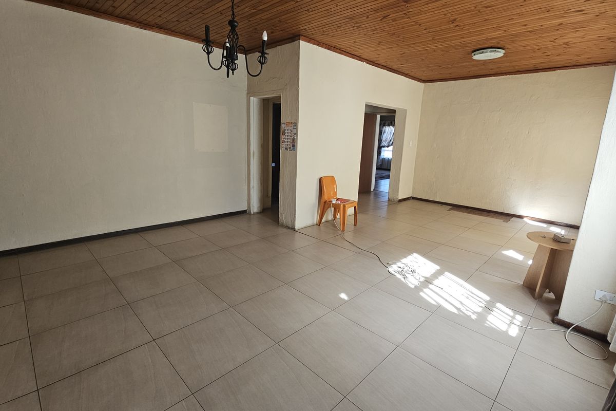 Spacious living area featuring large floor tiles and a distinctive timber tongue and groove ceiling, offering a blank canvas for interior design.