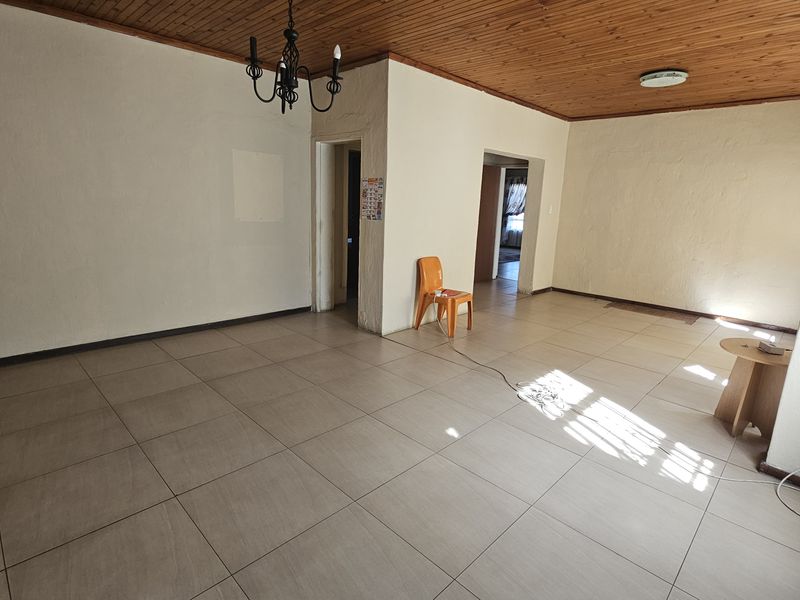 Spacious living area featuring large floor tiles and a distinctive timber tongue and groove ceiling, offering a blank canvas for interior design.