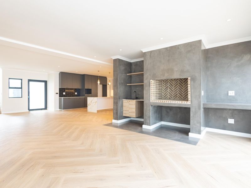 Spacious open-plan living area featuring herringbone timber flooring, a modern built-in fireplace, and a sleek kitchen with a stone-topped island.