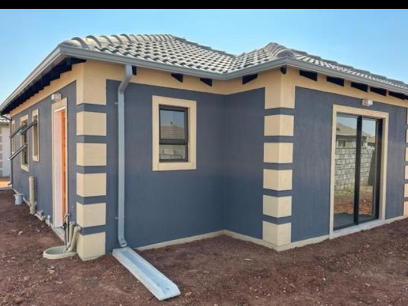 Rear view of a modern single-story house featuring a tiled roof, contrasting exterior paintwork, aluminium window frames, and a sliding glass door.