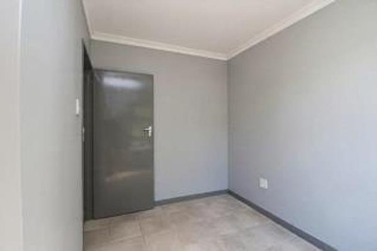 A clean, empty bedroom featuring neutral grey walls, tiled flooring, and a coved ceiling, providing a versatile space ready for personalization.