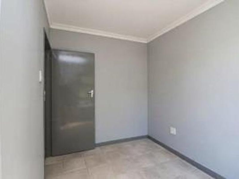 A clean, empty bedroom featuring neutral grey walls, tiled flooring, and a coved ceiling, providing a versatile space ready for personalization.
