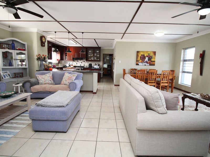 Spacious open-plan living, dining, and kitchen area featuring tiled floors, ceiling fans, and a functional kitchen layout with ample cabinetry.