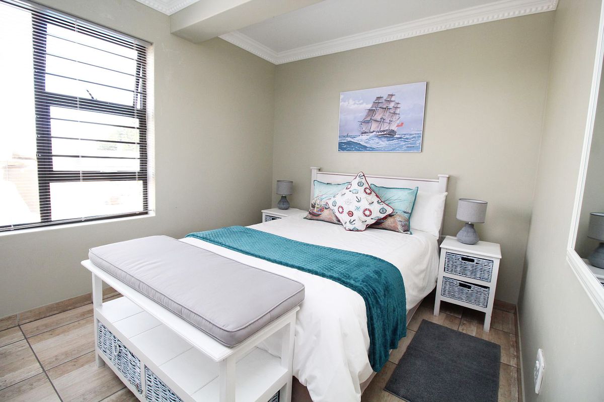 A well-maintained bedroom featuring tiled flooring, crown molding, and a window fitted with security bars for added peace of mind.
