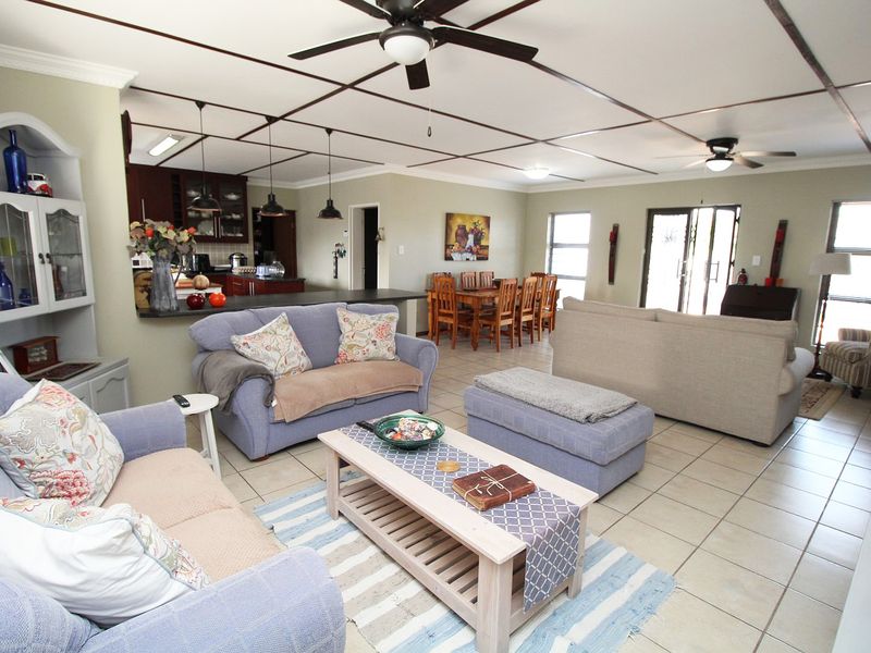 Spacious open-plan living, dining, and kitchen area featuring tiled floors, a coffered ceiling with fans, and direct access to the outdoor space.