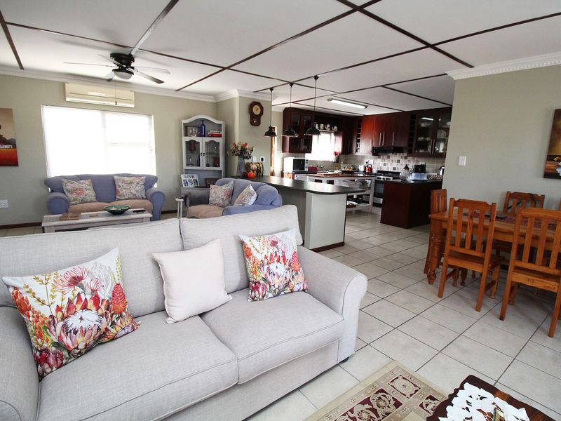Spacious open-plan living, dining, and kitchen area featuring tiled floors, a central kitchen island, and built-in cabinetry with integrated appliances.
