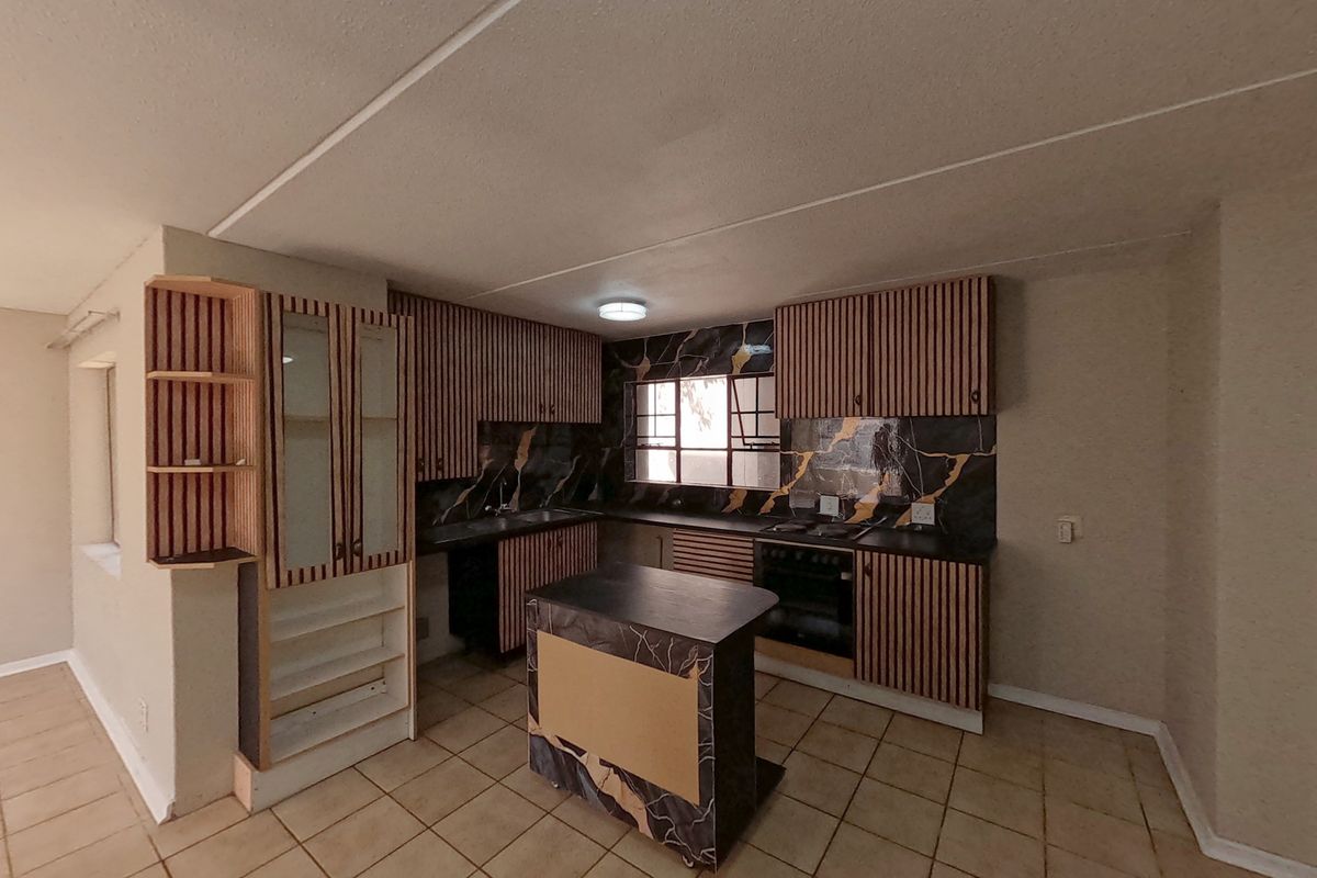 A functional kitchen featuring built-in cabinetry, a marble-effect splashback, integrated oven, hob, and a central island, offering a practical layout for culinary activities.