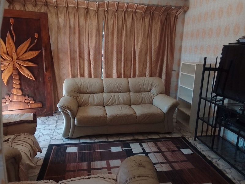 A living room featuring tiled flooring and a decorative carved wooden door, offering a dated aesthetic that could benefit from modern updates.