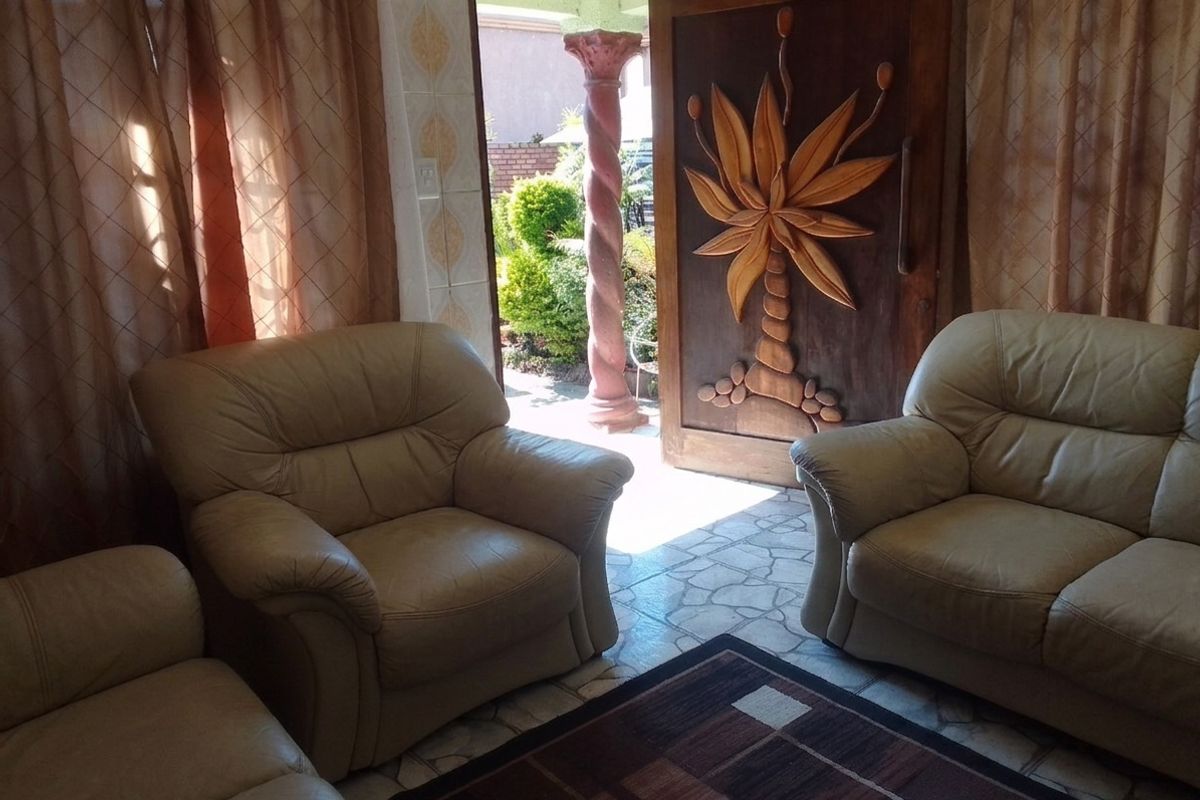 Living room area featuring tiled flooring and a distinctive carved wooden front door leading to an outdoor space with a decorative pillar.
