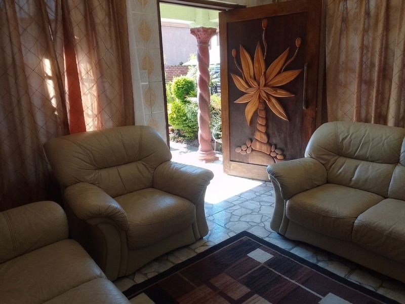 Living room area featuring tiled flooring and a distinctive carved wooden front door leading to an outdoor space with a decorative pillar.