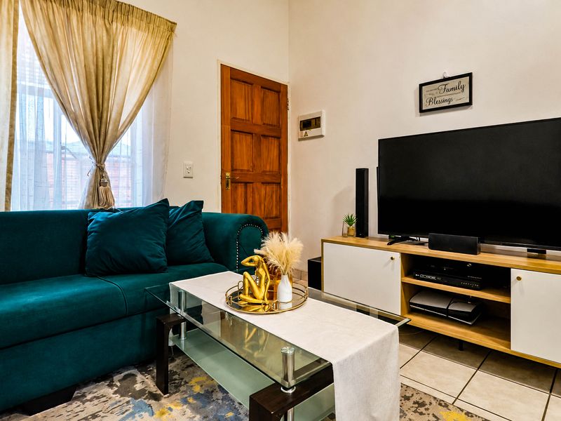 A cozy living room featuring tiled flooring and a classic timber door, providing a functional and comfortable space.