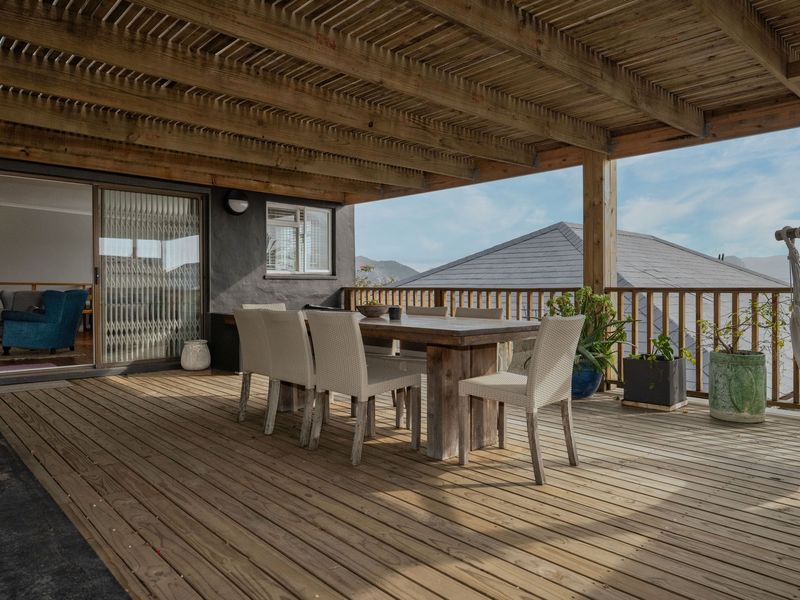 Spacious covered timber deck featuring a pergola, balustrade, and direct access to the interior through sliding glass doors, ideal for outdoor entertaining.