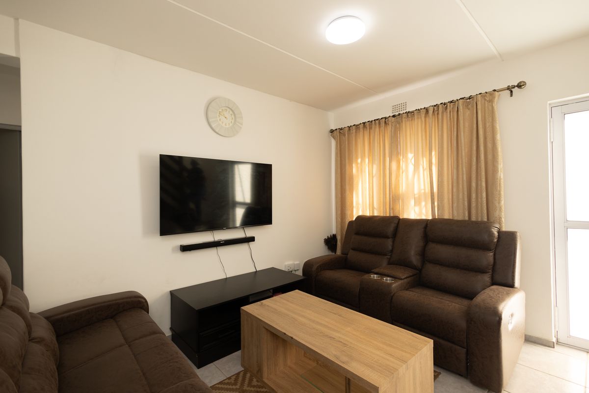 A functional living room featuring tiled flooring, a ceiling light fixture, and a glass door providing access to the exterior.