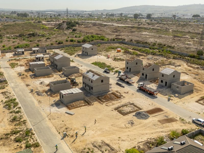 Aerial view of a residential development site showing multiple townhouse structures in various stages of construction with paved access roads.