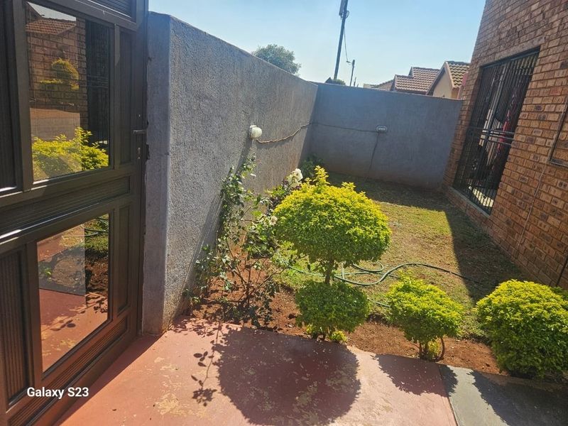 A private rear garden area featuring a paved patio, boundary walls, and security features, offering potential for outdoor landscaping and improvement.