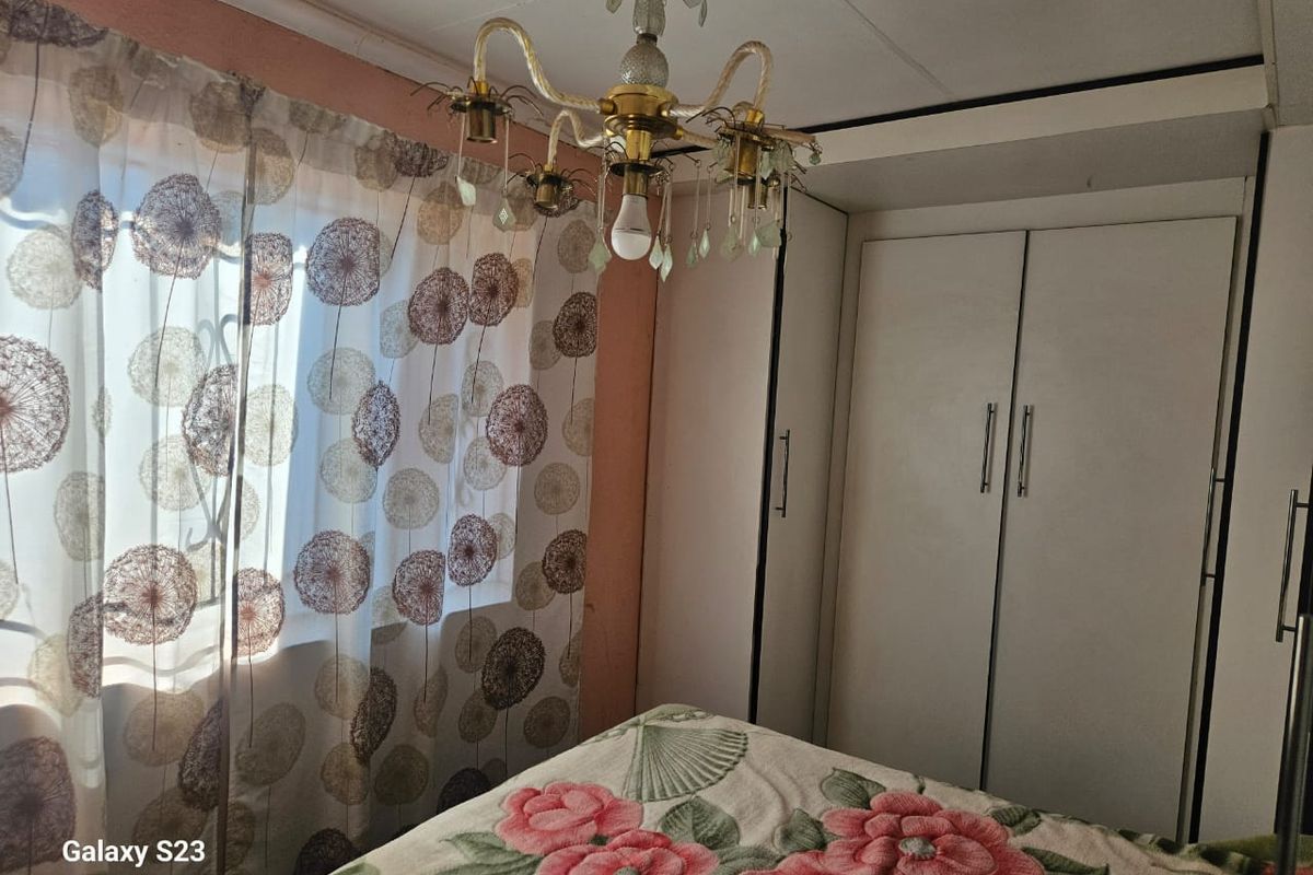 A bedroom featuring a built-in wardrobe and a decorative chandelier, providing essential storage and lighting.