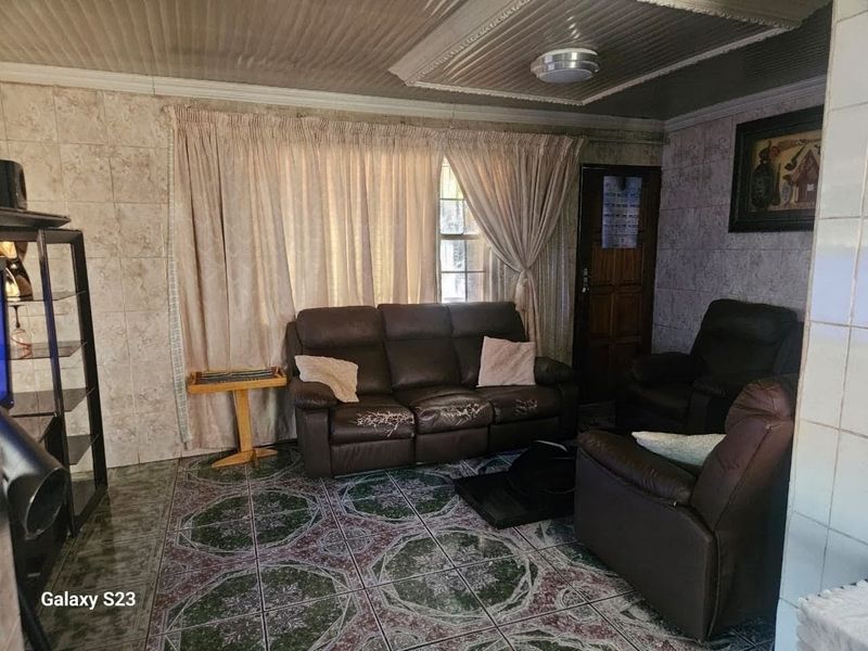 A living room featuring tiled walls and floors with decorative ceiling panels, offering a dated aesthetic that could benefit from modern updates.