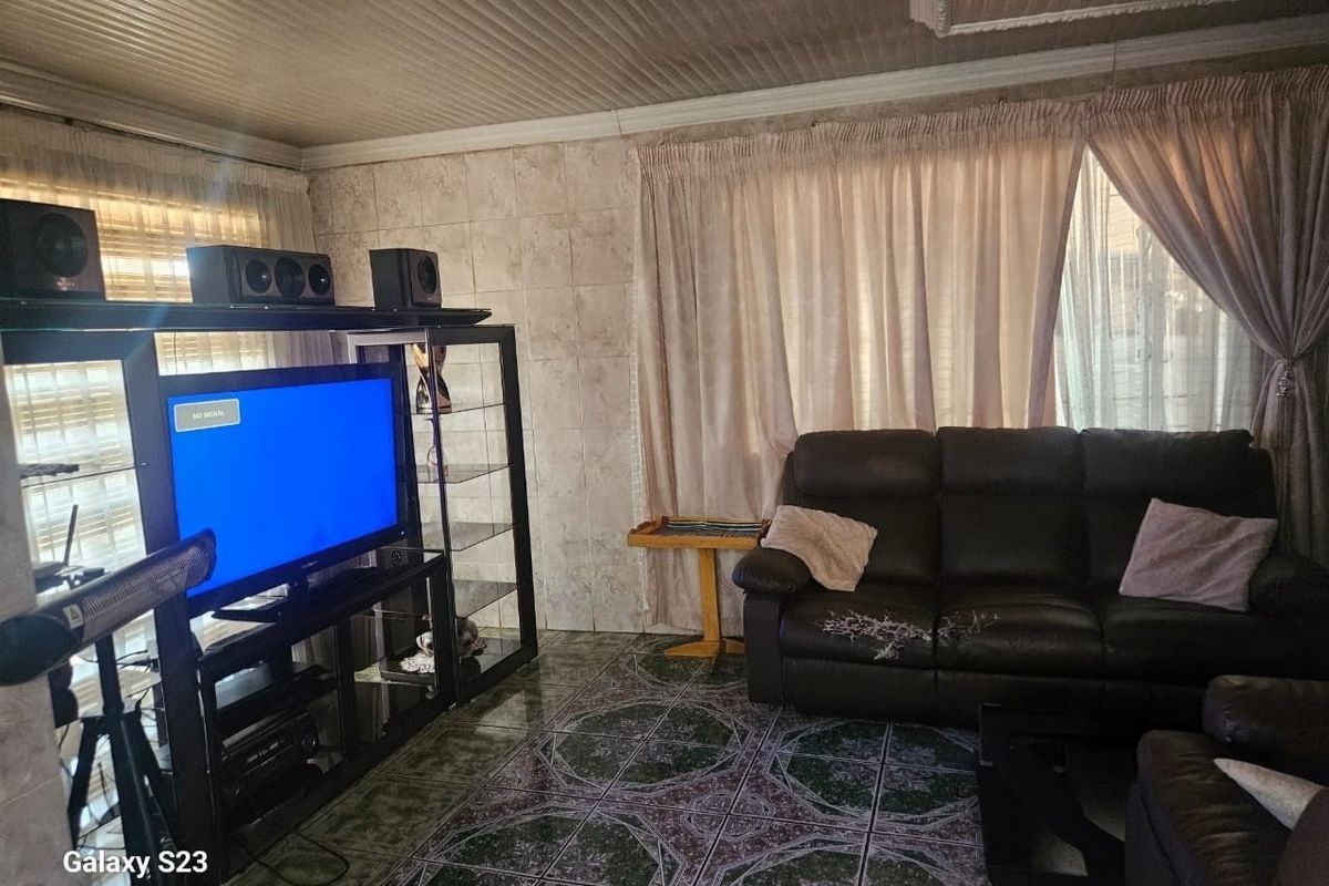 A living room featuring tiled flooring and wall finishes with a coved ceiling, offering a dated aesthetic ready for modernization.