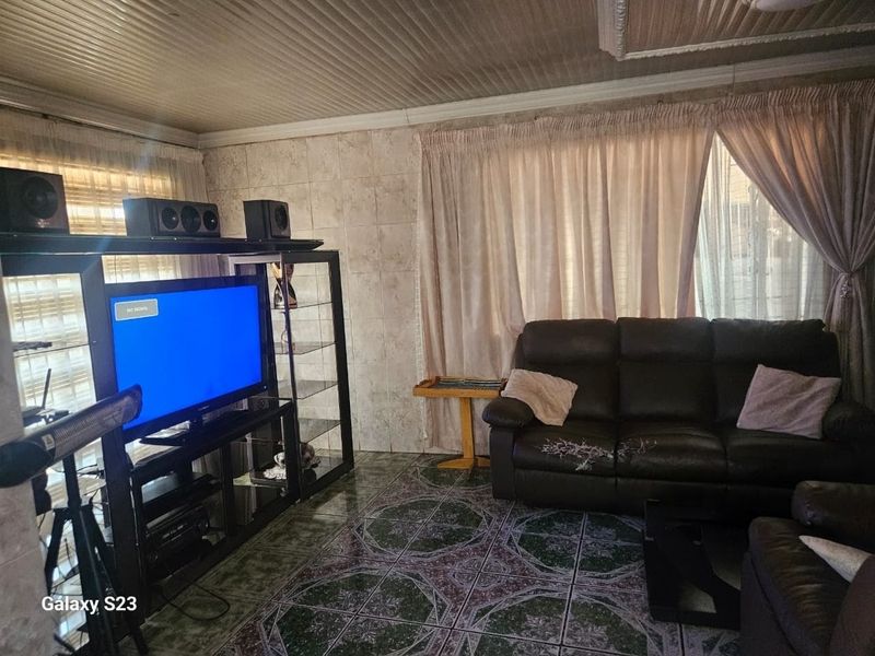 A living room featuring tiled flooring and wall finishes with a coved ceiling, offering a dated aesthetic ready for modernization.