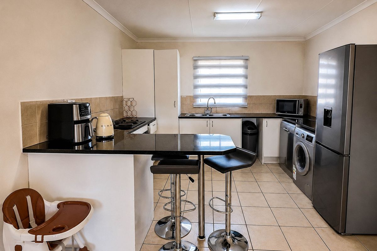 A functional kitchen featuring granite countertops, a breakfast bar, built-in cabinetry, and tiled flooring, offering a practical layout for daily use.