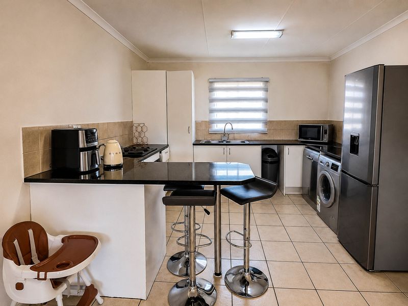 A functional kitchen featuring granite countertops, a breakfast bar, built-in cabinetry, and tiled flooring, offering a practical layout for daily use.