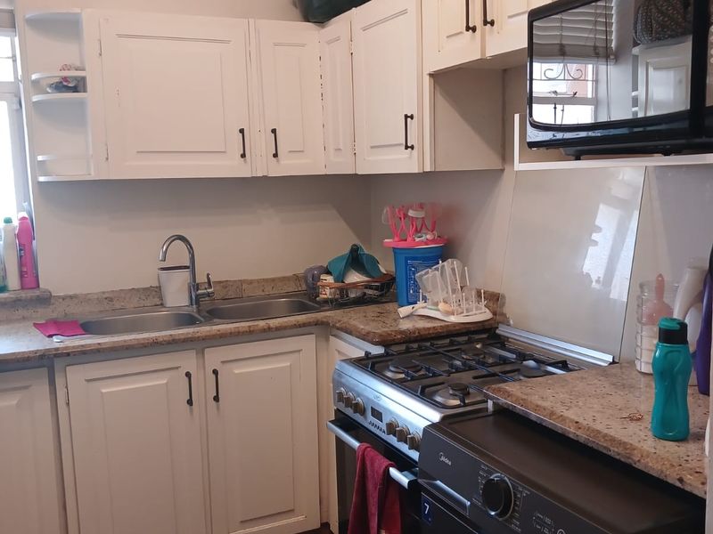Compact kitchen featuring white cabinetry, granite countertops, a gas stove, and tiled flooring, providing a functional workspace for daily cooking needs.
