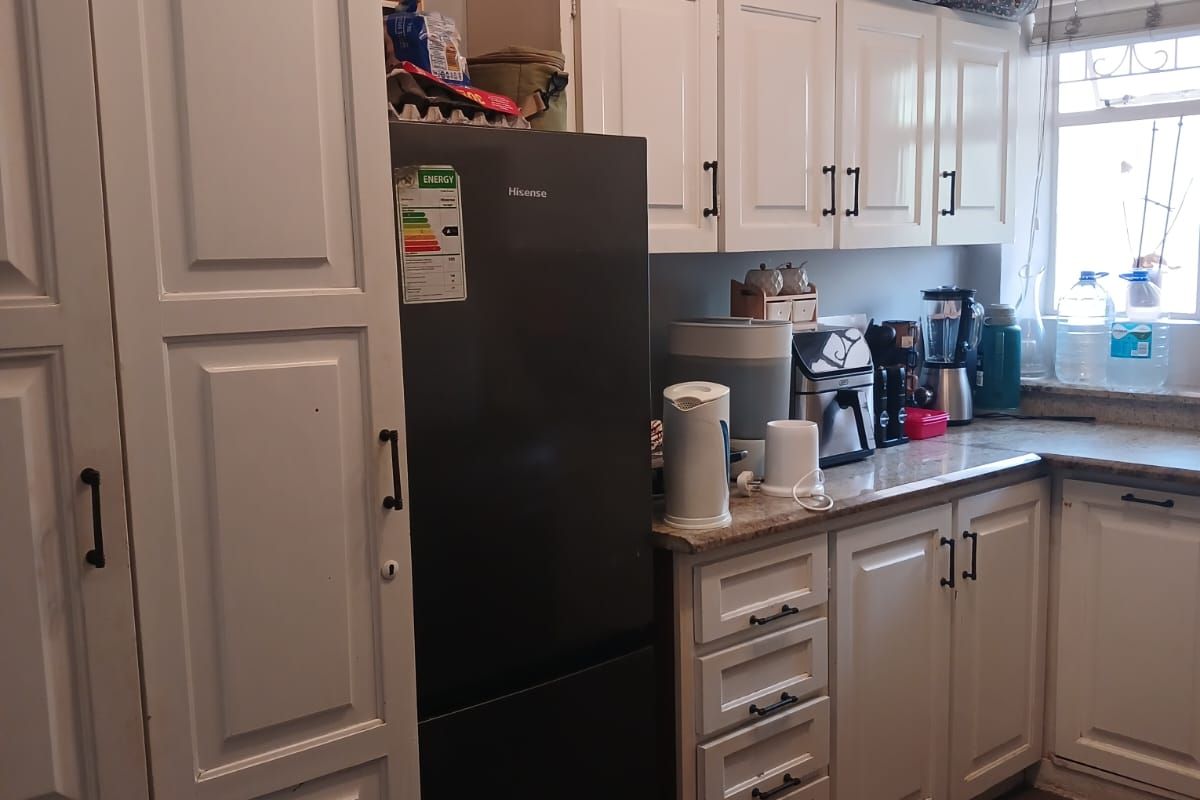 A functional kitchen featuring white cabinetry, stone countertops, and tiled flooring, offering a practical layout with natural light from the window.