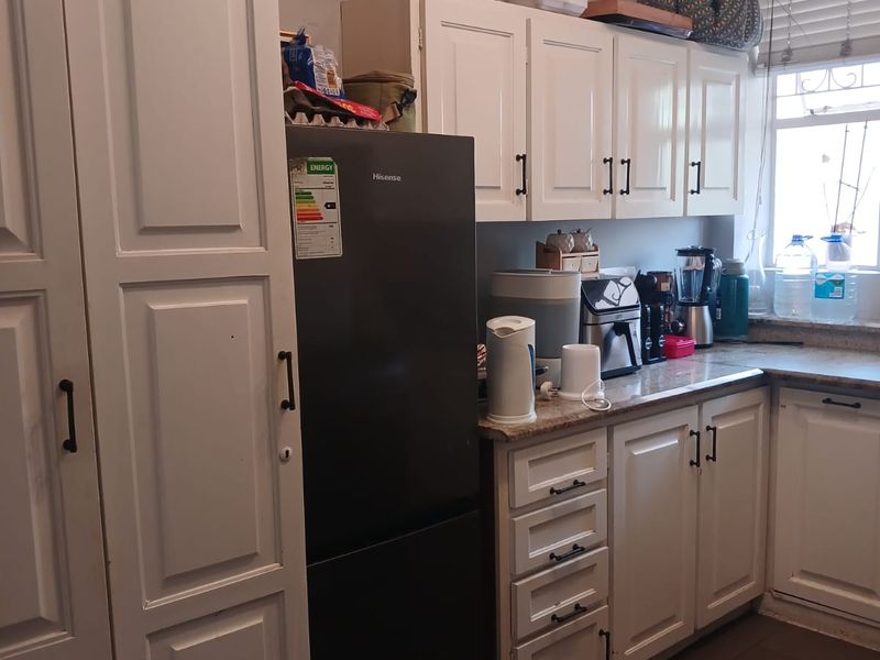 A functional kitchen featuring white cabinetry, stone countertops, and tiled flooring, offering a practical layout with natural light from the window.
