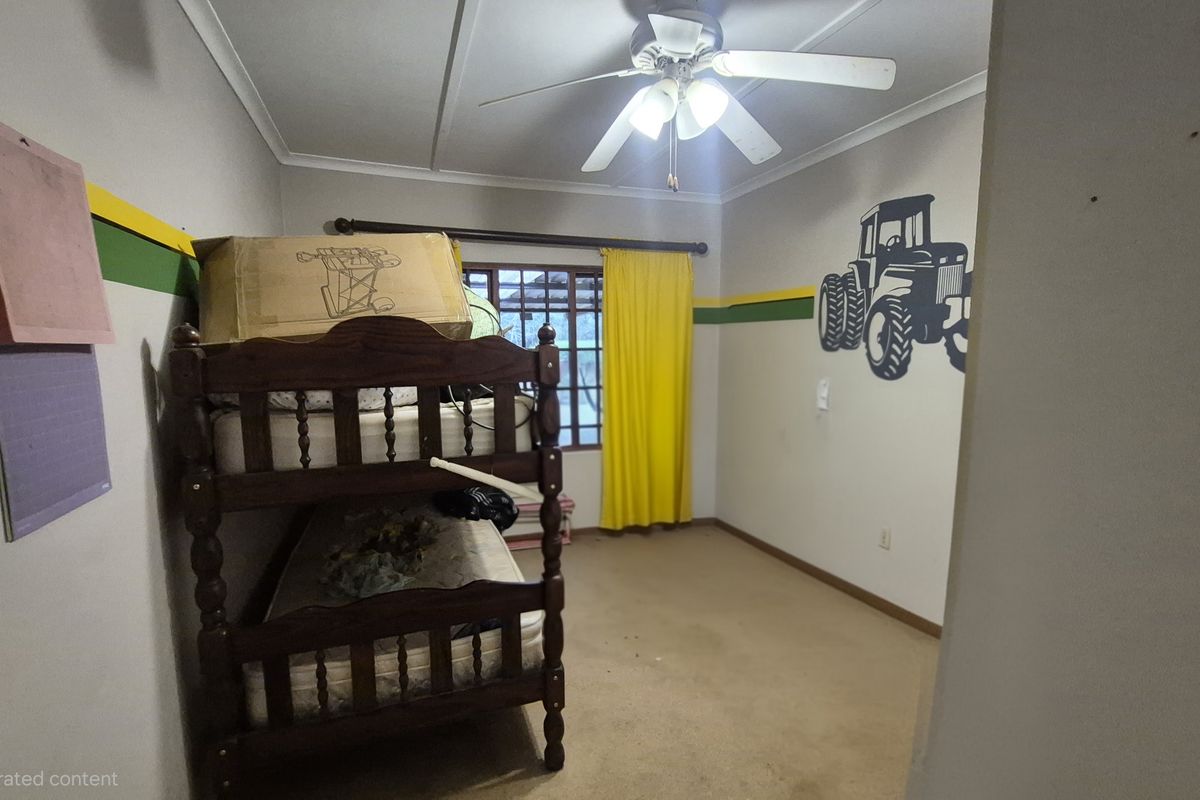 A bedroom featuring a ceiling fan, carpeted flooring, and a window with yellow curtains.