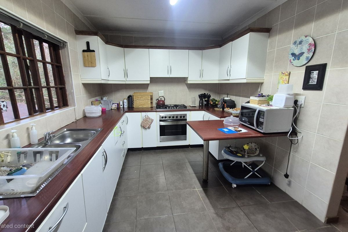 A functional kitchen featuring white cabinetry, laminate countertops, a built-in oven with gas hob, and tiled finishes throughout.